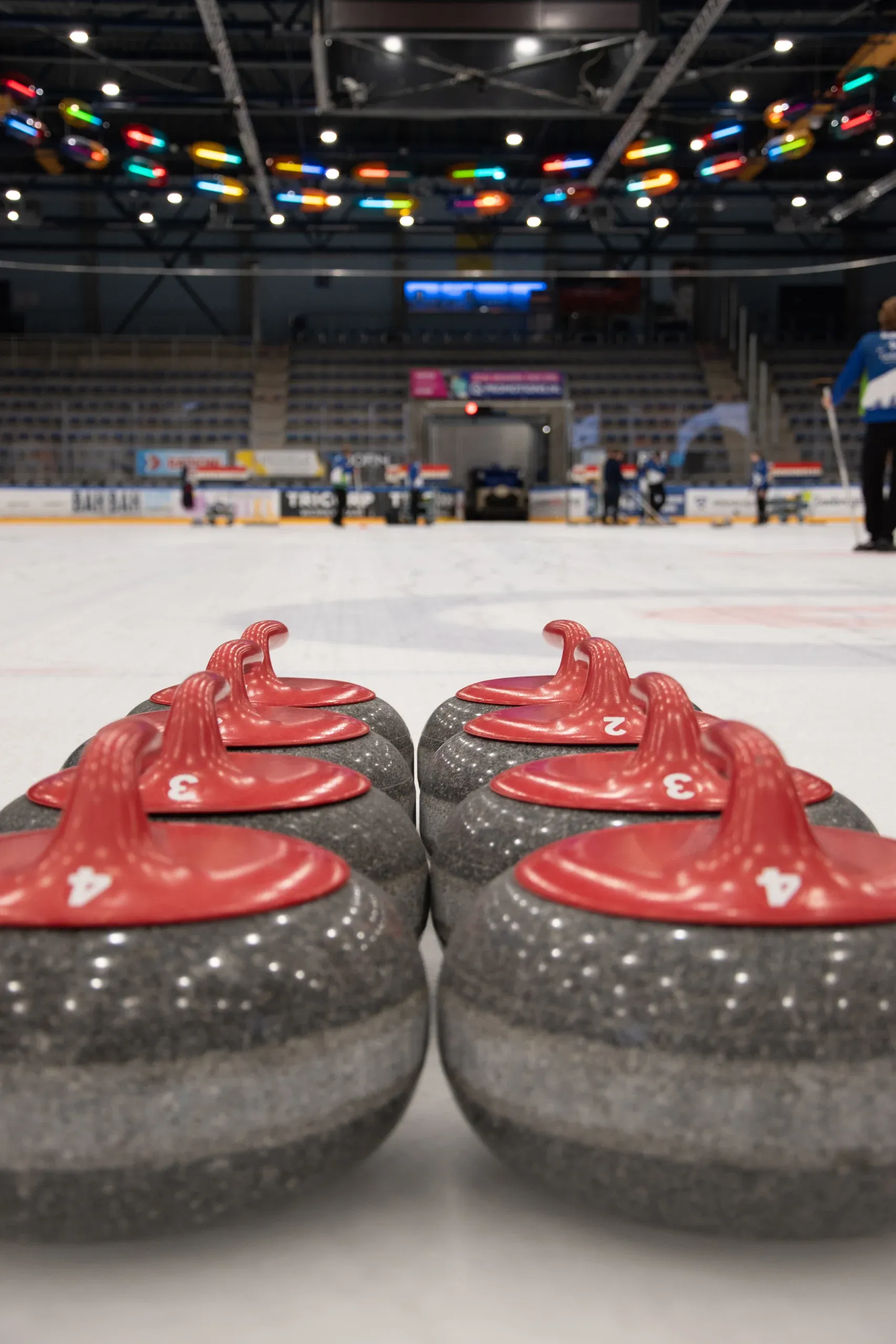 Row of curling stones with red handles on the ice at IJssportcentrum Tilburg